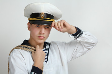  sailor holding his hand a cap with a rope on his shoulder