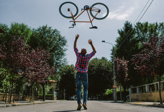 Rear view of man throwing a bicycle on road
