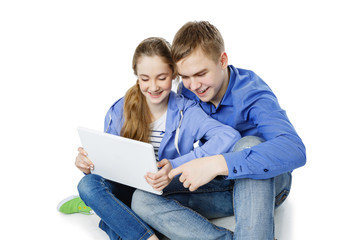 Teen boy and girl sitting with tablets