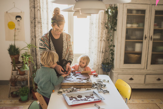 Mother helping daughters while preparing cookies
