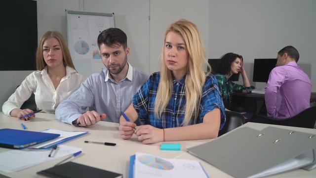 Portrait angry focused business team looking at the camera. Young group of people wearing in casual colored shirt holding pen. Nervous wrought-up team in creative office.