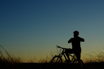 Adult cyclist silhouette having rest dusk time