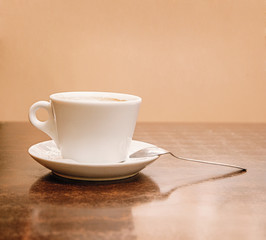 Coffee cup side view on wooden table. A lot of space for text on wall on background