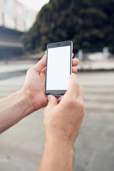 Making photo outdoors by smartphone. Hands holding and touch on blank smartphone with clipping path for screen.