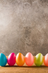 Easter eggs on wooden table and stone background