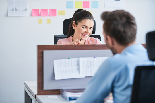 Office flirt - attractive woman flirting over desk with her coworker