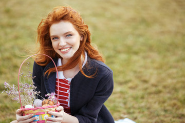 Happy pretty girl holding picnic basket with easter eggs outdoors