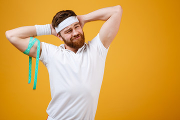 Confident sports man posing with measuring tape on his biceps