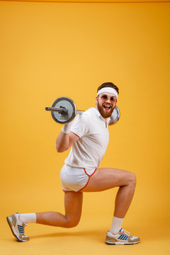 Side view of a retro fitness man doing squats with barbell