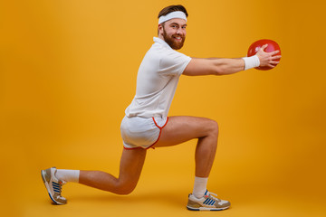 Cheerful young sportsman make sport exercises holding ball.