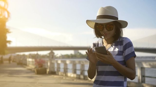 Asian woman tourist using mobile smart phone with Tower Bridge background