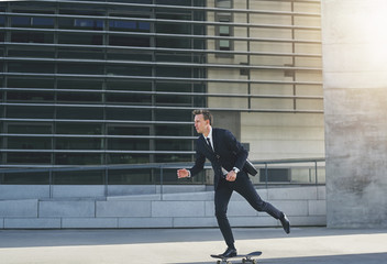 Fototapeta na wymiar Sunlit businessman moving forward on a skateboard
