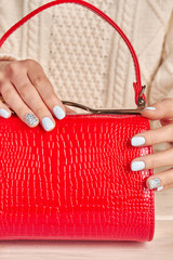 Close-up of red female handbag and manicure.