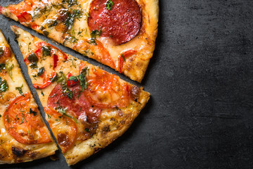 Traditional italian pizza. Sliced. Top view black stone background