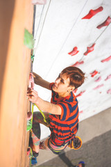 The girl climbs on the climbing wall.