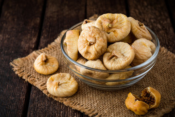 Dried figs in glass bowl on wooden background.