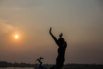 Woman biking hands at sunset. 