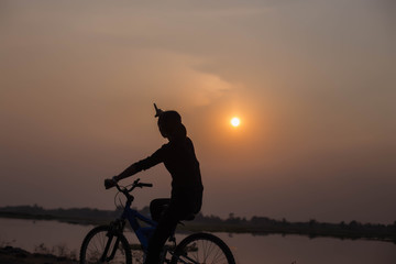 Woman biking hands at sunset. 