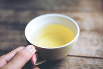Hand holding clay tea mug on vintage wooden table