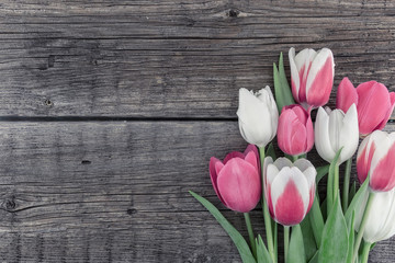 Frame of tulips on rustic wooden background with copy space for message. Spring flowers. Greeting card for Valentine's Day, Woman's Day and Mother's Day. Top view