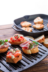 Set of bruschetta on black grill pan on wooden background. Tasty antipasto.