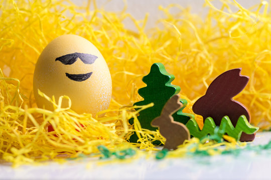 Happy easter: emoji as easter egg in yellow gras smiling face with sunglasses
