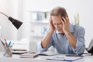Gray-haired male person having headache