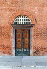 Old vintage curch door with red brick wall