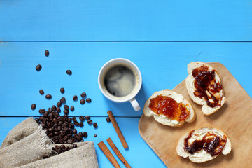 breakfast on a blue table / Flat layout with espresso, coffee beans, toast with fruit jam, top view 