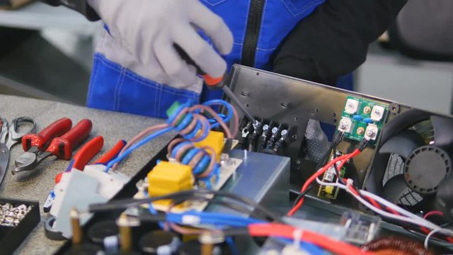 Electrician assembles equipment into electrical control cabinet, fuse box. 4K.