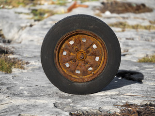 Old worn car wheel with rusty rim.