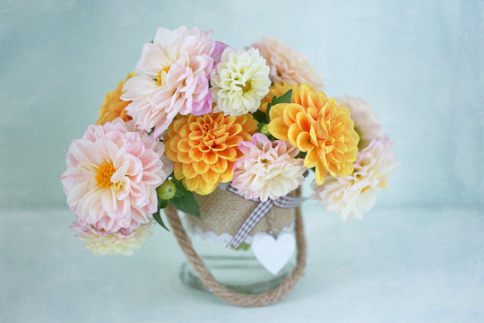Beautiful bouquet of a yellow and pink dahlias on a light green background. 
