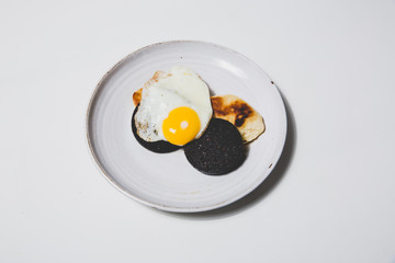 Fried egg with black pudding on white background