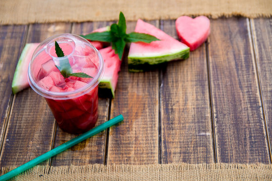 Watermelon cocktail with slice on wooden background. Heart carved from watermelon. Top view. Copy space.