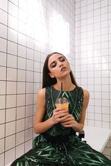 Woman with closed eyes sitting and drinking juice in cafe