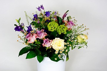 Bouquet of flowers in a white vase against a white background.