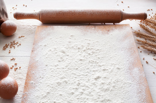 Baking concept on white wood background, sprinkled flour with copy space