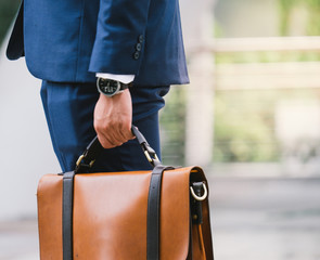 Closeup Of A Businessman wear the watch and Holding leather Briefcase Going To Work with the...