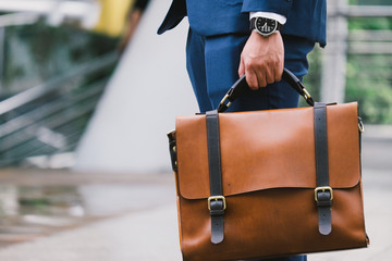 Closeup Of A Businessman wear the watch and Holding leather Briefcase Going To Work with the...