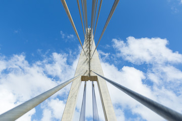 From below shot of bridge structure with wires on background of blue clear sky