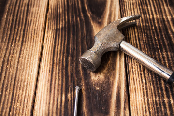 a nail and a hammer on wooden background