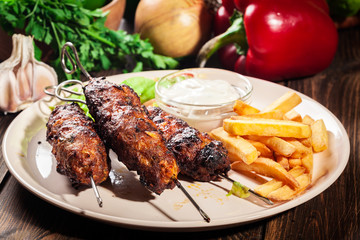 Grilled shish kebab served with fried chips and salad