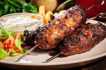 Grilled shish kebab served with fried chips and salad
