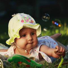 Beautiful baby girl lying on the grass. Nature, holidays, childhood concept.