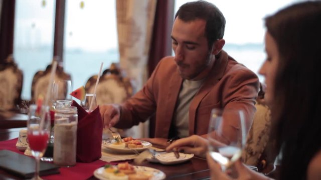 Couple enjoying the travel on a boat in restaurant with the ocean in background