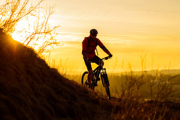 Fototapeta na wymiar Silhouette of Enduro Cyclist Riding the Mountain Bike on the Rocky Trail at Sunset. Active Lifestyle Concept. Space for Text.
