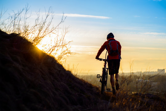 Silhouette of Enduro Cyclist with Mountain Bike on the Rocky Trail at Sunset. Active Lifestyle Concept. Space for Text.