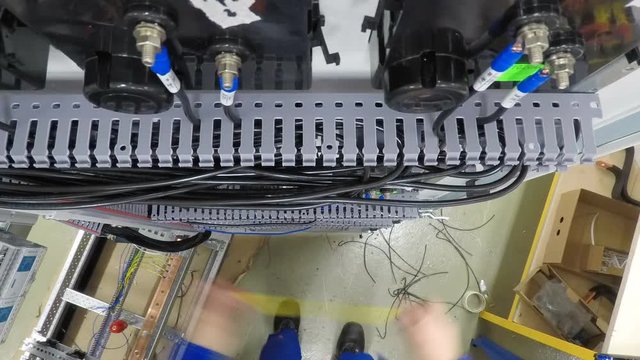 Close-up, top view. Electrician engineers hands equipment into electical control cabinet, fuse box. 4K.