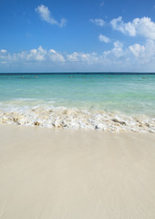 The Caribbean sea and the beautiful beach. Small waves hitting the shore on a sunny day.