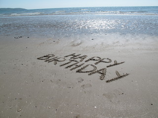 Happy birthday scripted in coast sand